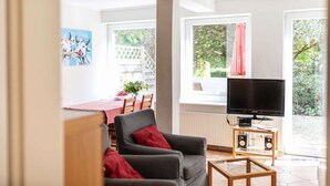 A living room with a grey sofa, a TV, and a small wooden table.