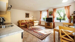 A cozy living room with a sofa, TV, and dining area.
