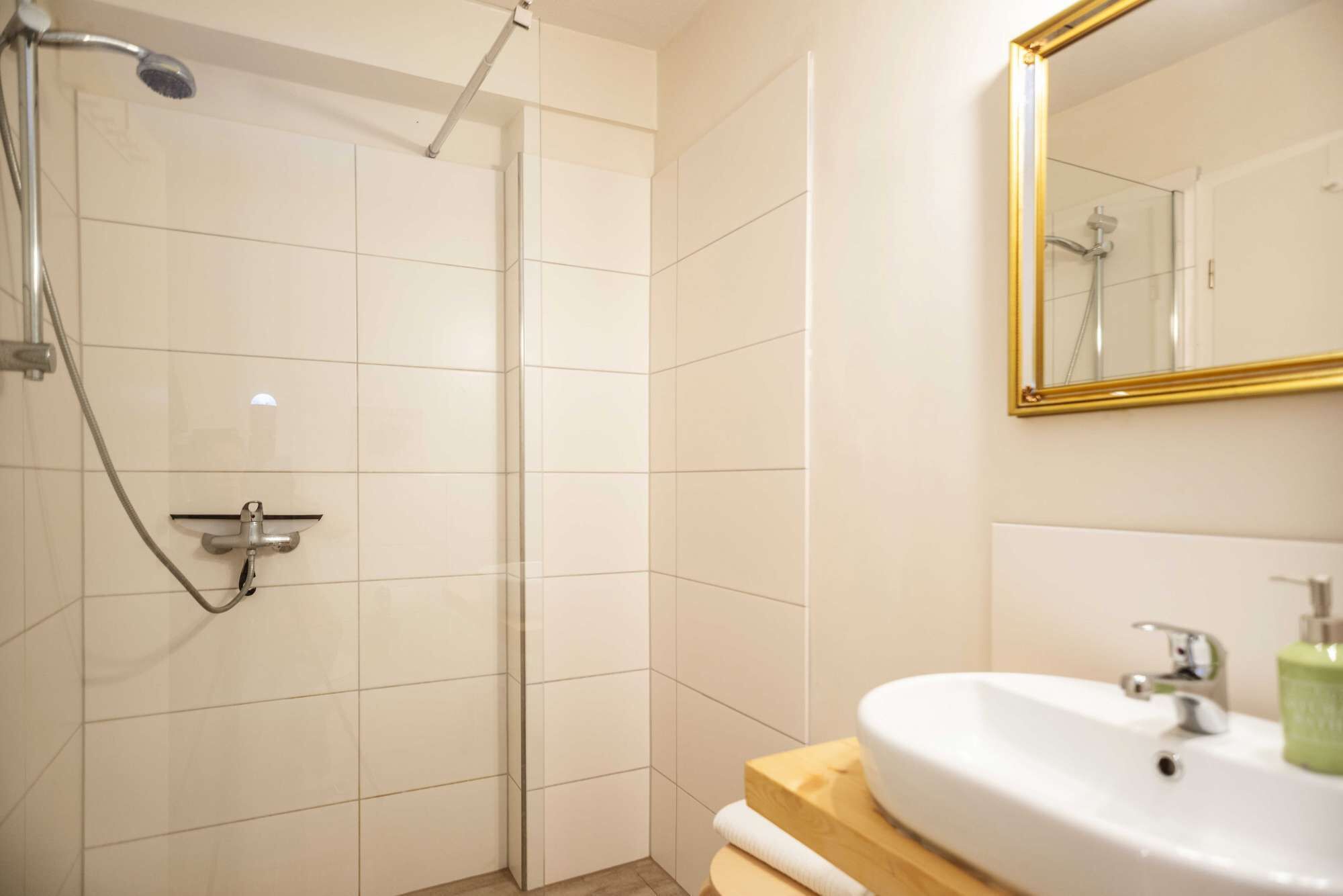 A bathroom with a shower, a sink, and a mirror.