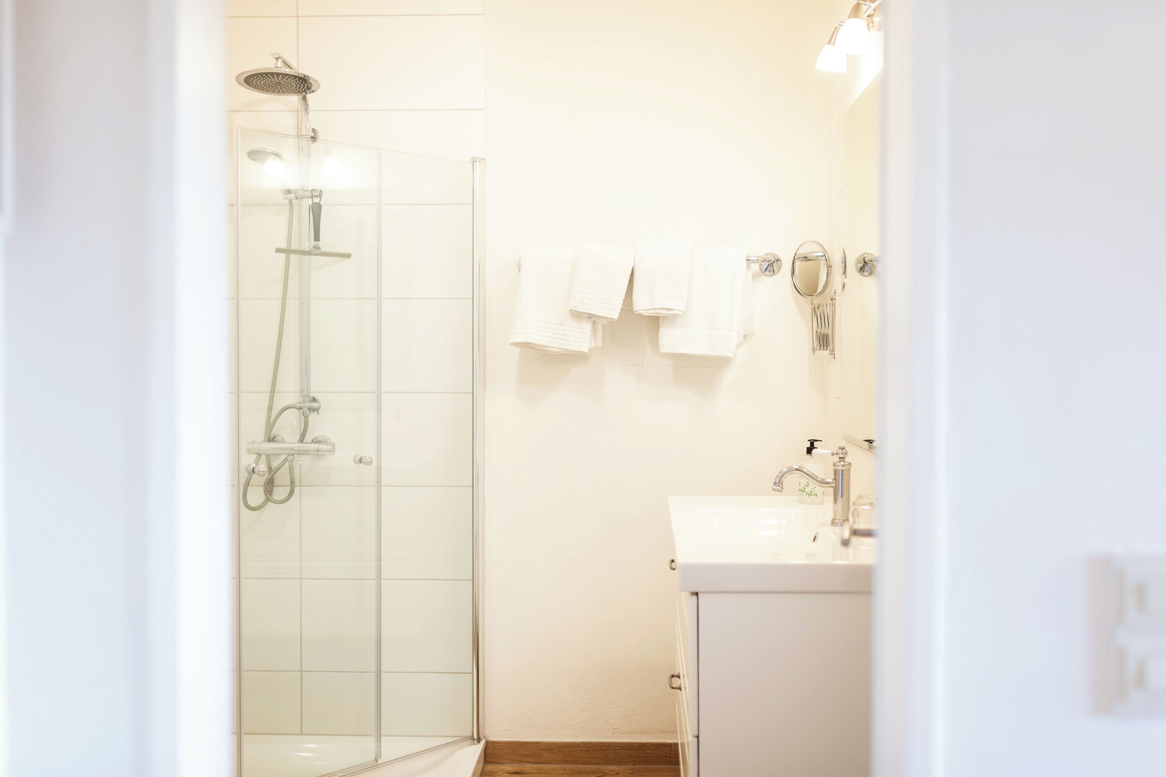 Ein modernes Badezimmer mit einer gläsernen Dusche, einem weißen Waschbecken und ordentlich gefalteten Handtüchern.