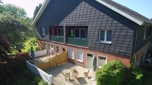 Una casa de dos plantas con un balcón, un porche cubierto y un jardín.
