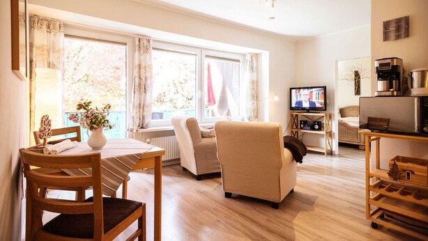 Una sala de estar acogedora con una mesa de comedor de madera, un sofá y un televisor.