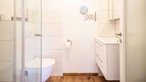 Un baño pequeño con mampara de vidrio, inodoro, lavabo y espejo.