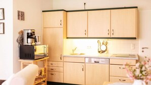 Una cocina compacta con armarios de madera, una cafetera, un microondas y un lavavajillas.
