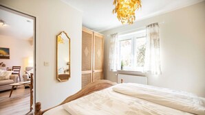 Un dormitorio con una cama de madera, un espejo grande, una ventana con cortinas y vistas a una sala de estar.