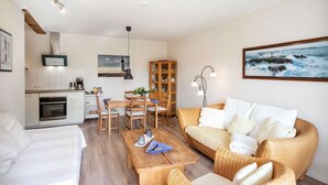 Una sala de estar acogedora con sofá, una mesa de comedor y una zona de cocina.