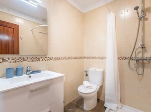 Un baño con inodoro, lavamanos y ducha.