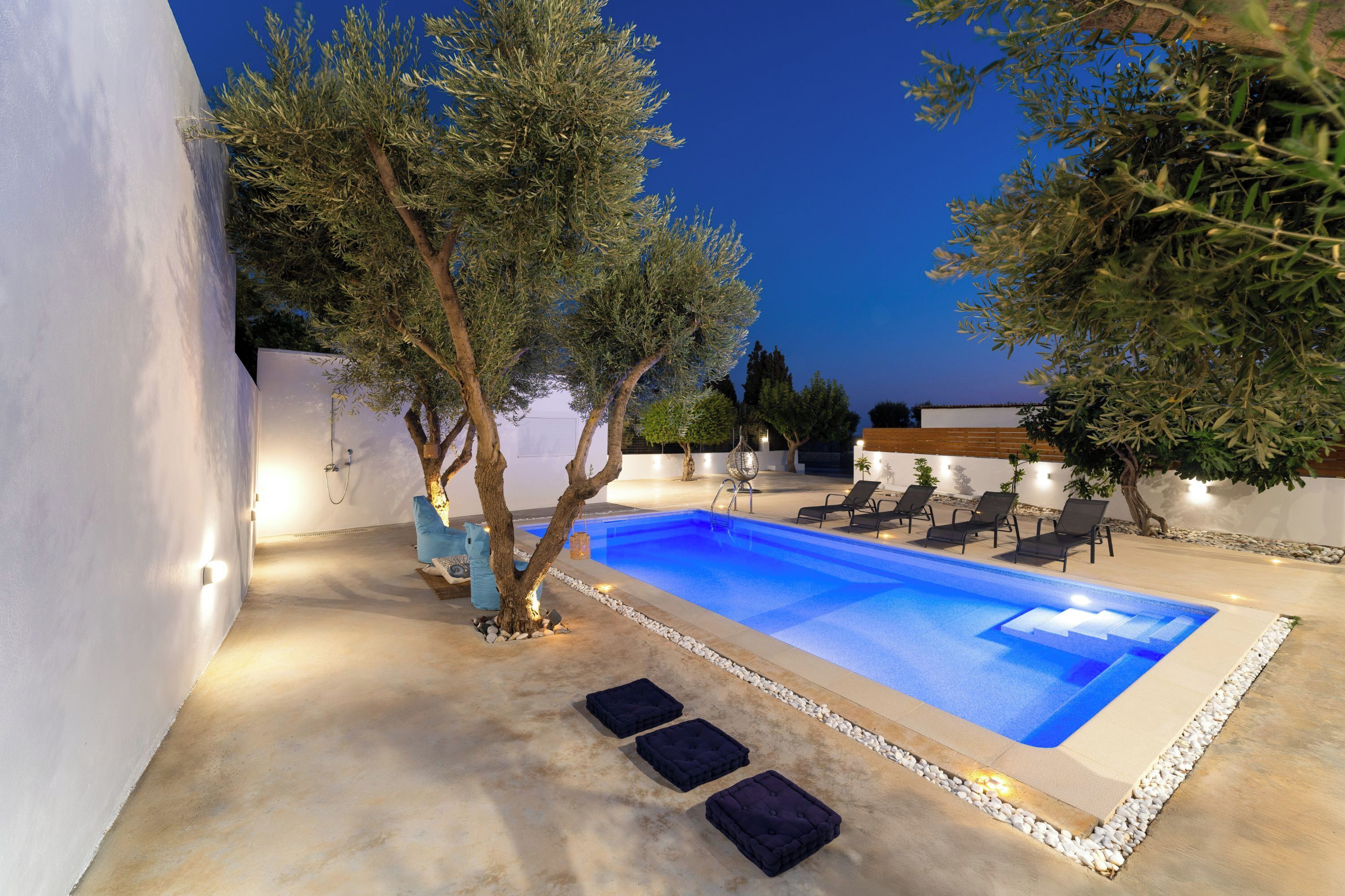 Una piscina con riflessi blu, circondata da pareti bianche e alcuni alberi.