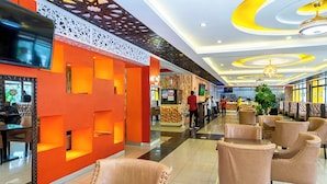 A modern hotel lobby with a central seating area, a reception desk, and a decorative wall with a TV screen. - Nur Complex Hotel  (Nairobi)