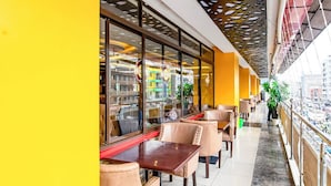 A restaurant with outdoor seating, large windows, and a yellow wall. - Nur Complex Hotel  (Nairobi)