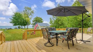 Une terrasse en bois avec une table et des chaises, un drapeau américain et une vue sur l’océan.