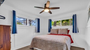 A bedroom with a bed, a ceiling fan, and windows with curtains. - North Bound 25 Cottage #3 (Lexington)