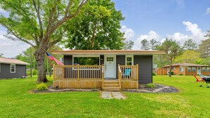 A small, single-story house with a front porch, a mailbox, and a flag. - North Bound 25 Cottage #3 (Lexington)
