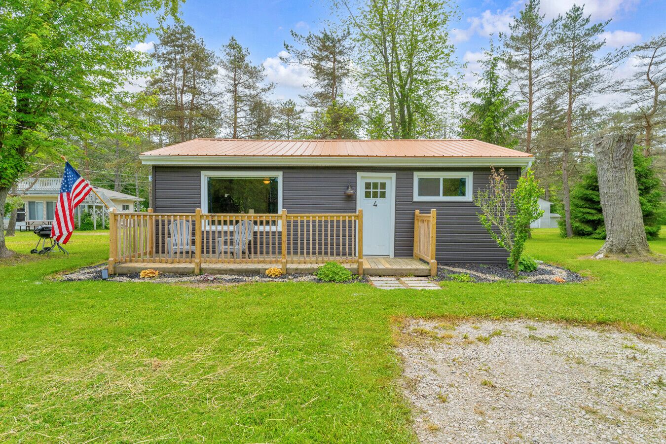 Une petite cabane avec une véranda, un drapeau et une pelouse bien entretenue.