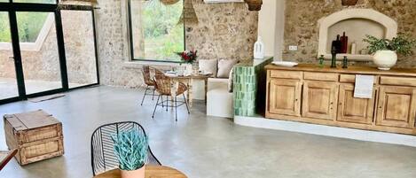 Una cocina amplia con ventanas grandes, una pared de piedra y un armario de madera.