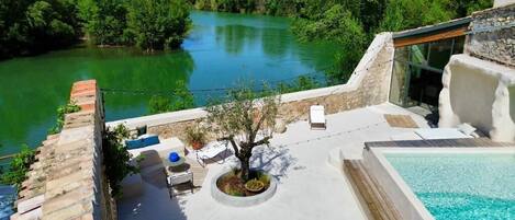 Une terrasse sur le toit avec une piscine, un espace salon et une vue sur une rivière.