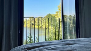 Une chambre avec une grande fenêtre donnant sur un lac et des arbres.