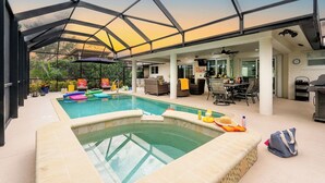 A covered outdoor pool area with lounge chairs, a barbecue, and a dining area.