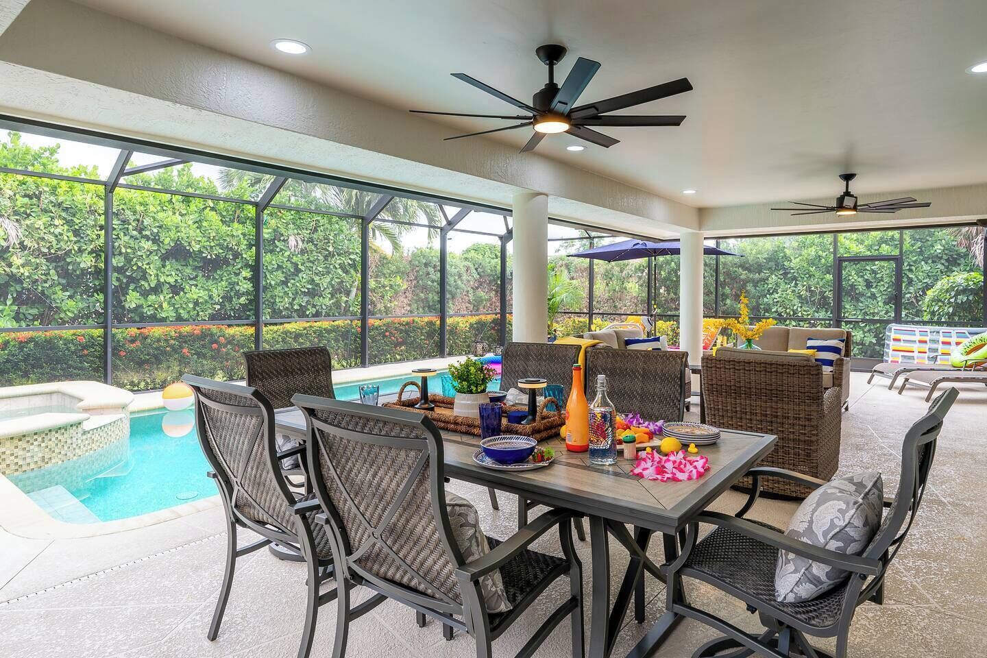 An outdoor patio with a pool, dining area, and ceiling fans.