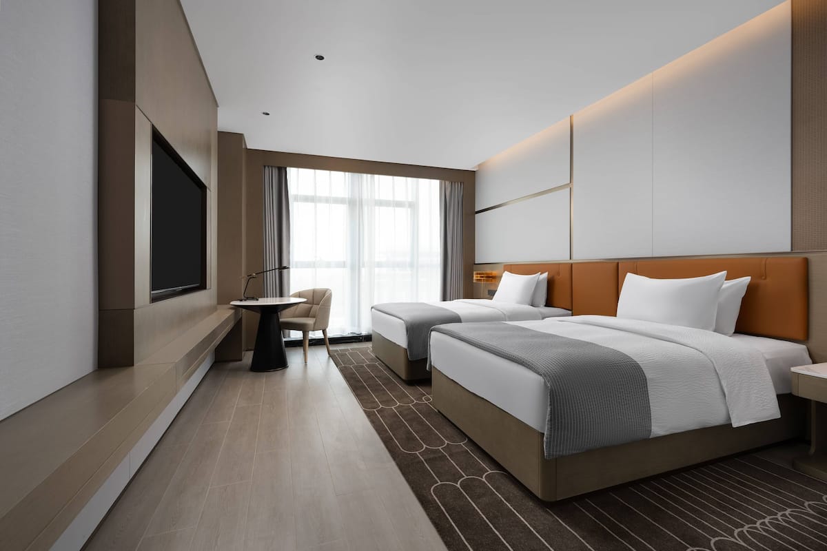Una habitación de hotel moderna con dos camas, un escritorio y un televisor.