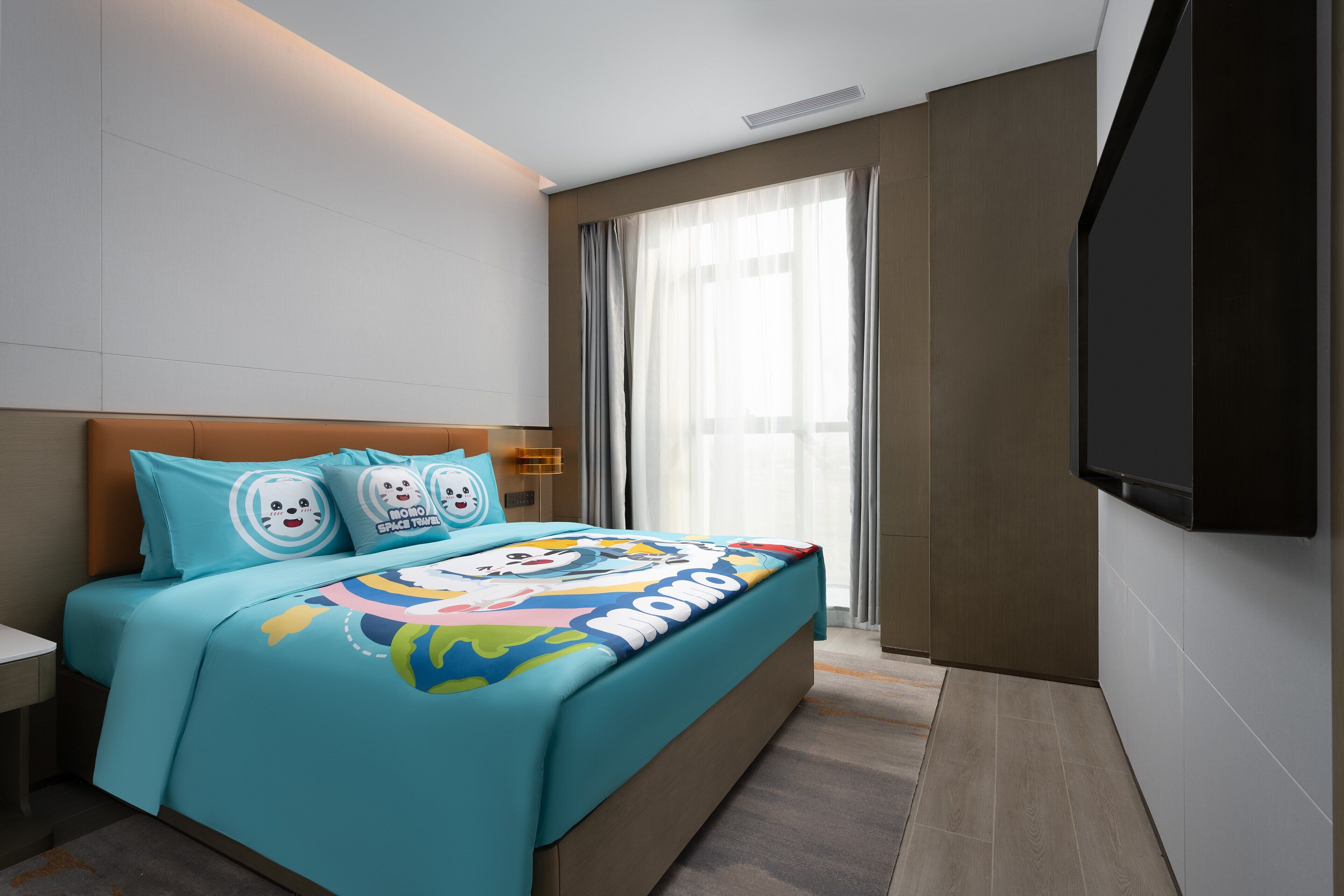 Una habitación de hotel moderna con una cama grande, un televisor de pantalla plana y un ventanal con cortinas translúcidas.