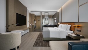 Una habitación de hotel moderna con una cama grande, mesitas de noche, un escritorio, una silla y un televisor.