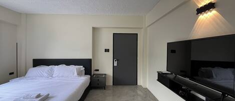 A hotel room with a bed, bedside table, nightstand, and a built-in TV.