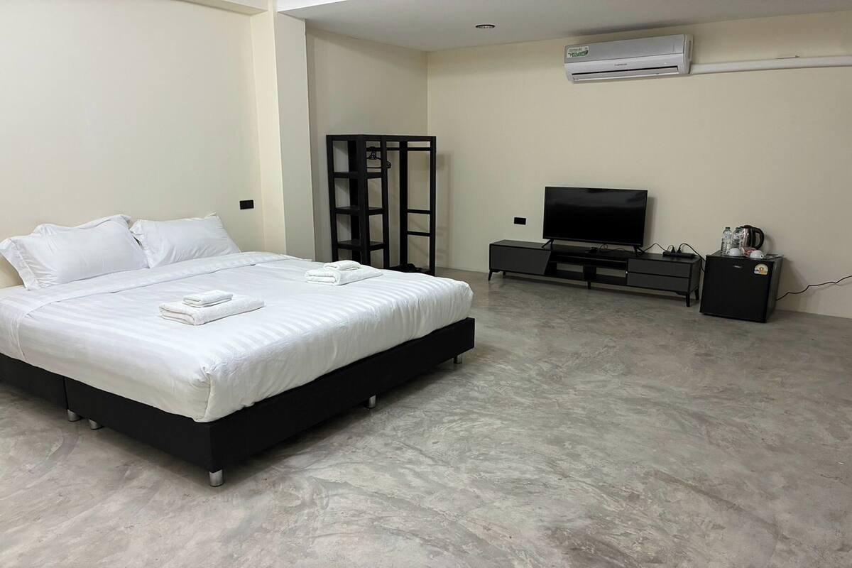 Un dormitorio con cama, televisión, armario y aire acondicionado.