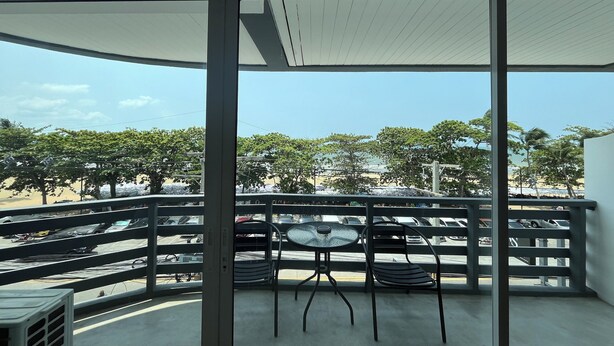 Un balcon donnant sur un parking et des arbres.