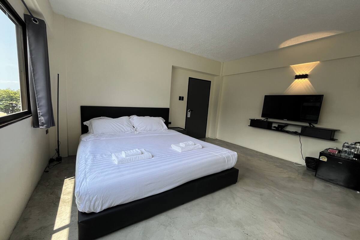 Una habitación de hotel con una cama grande, un televisor montado en la pared y una puerta.