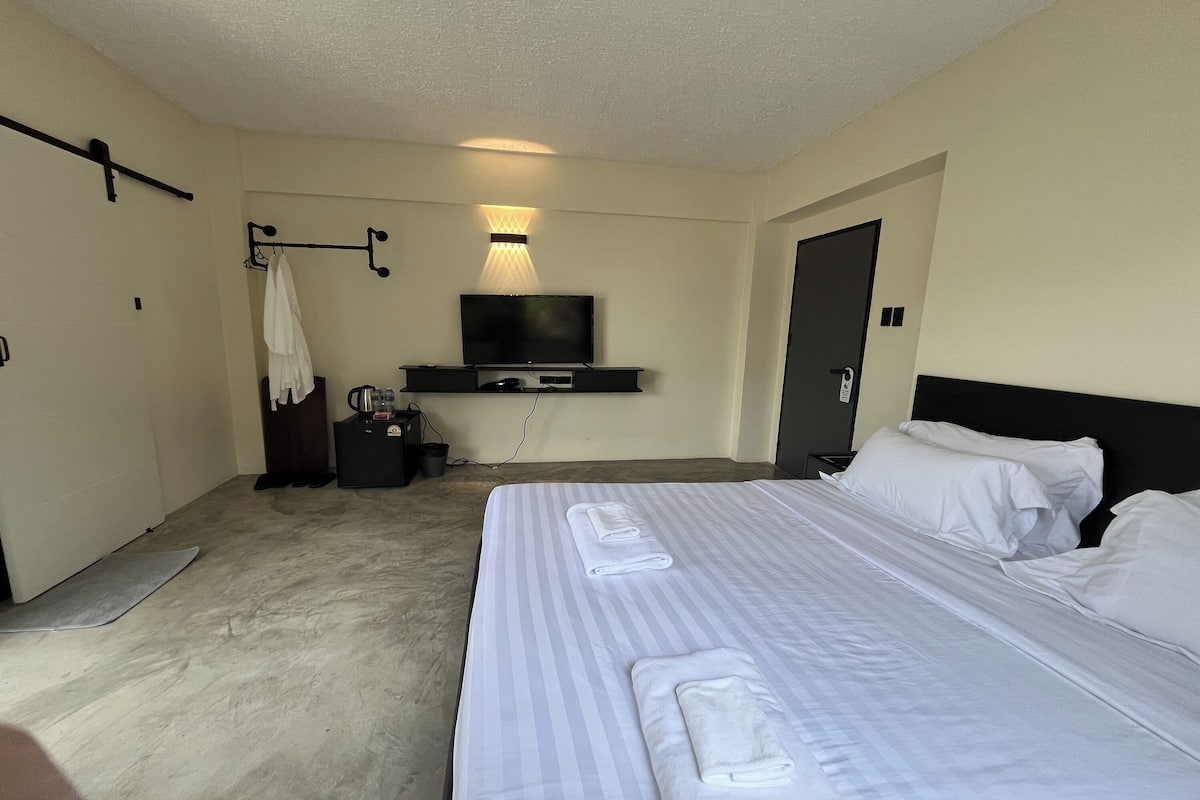 Una habitación de hotel con una cama, un televisor, un escritorio y una puerta.