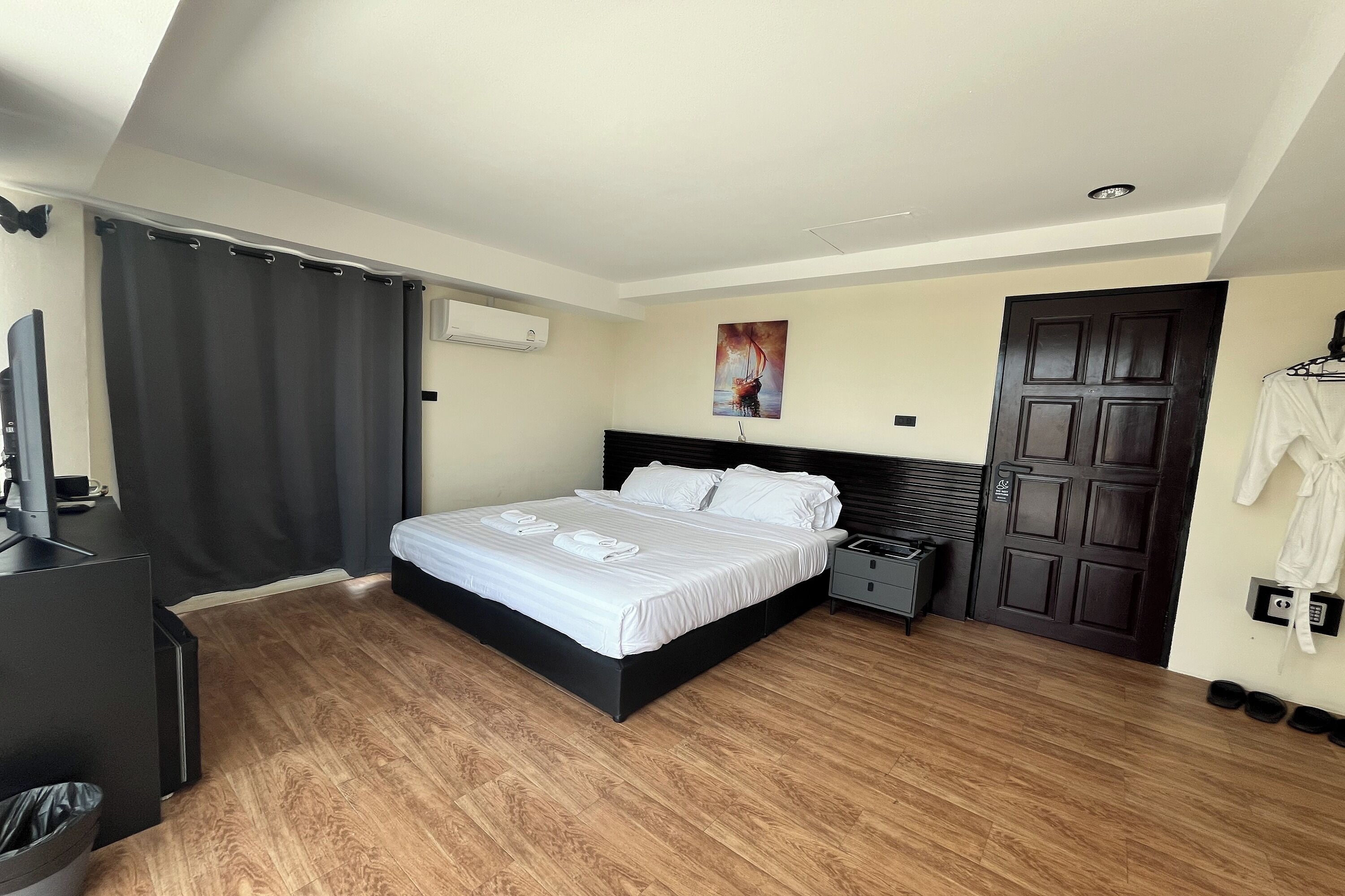 A hotel room with a bed, a desk, a TV, a coat rack, and a door.
