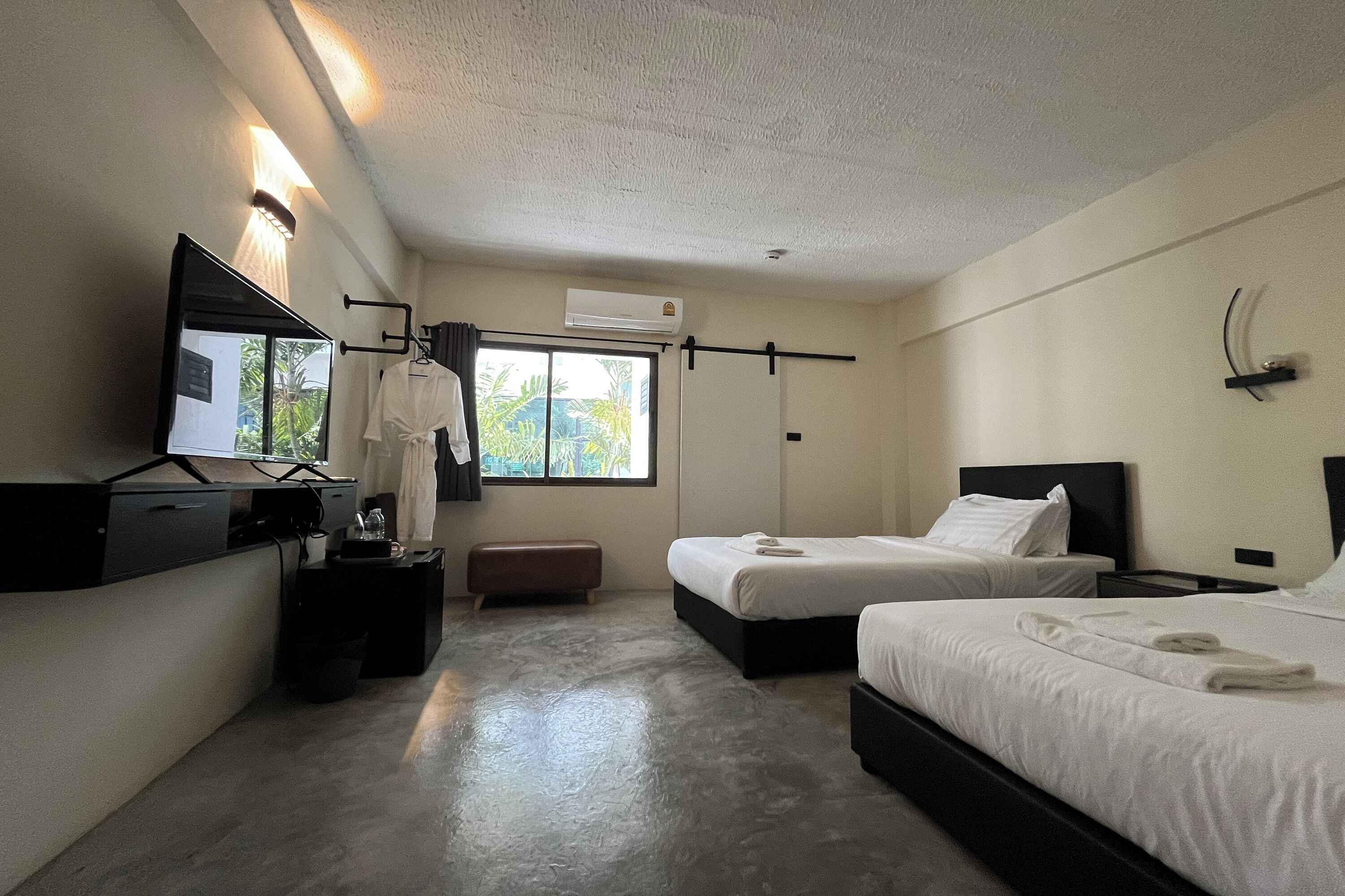 A hotel room with a bed, bedside table, TV, and a window with curtains.