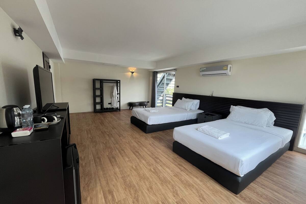 Habitación de hotel con dos camas, un escritorio con hervidor y un armario.