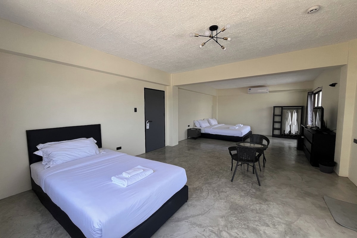 Habitación de hotel con dos camas, un escritorio, una silla y una lámpara en el techo.