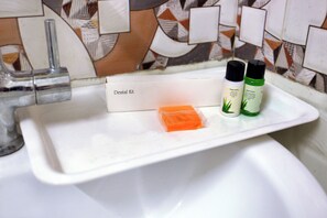 A bathroom sink with a dental kit and two bottles of mouthwash. - Hotel Global Inn by Quality Inn  (New Delhi)