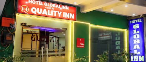 The exterior of Hotel Global Inn, featuring a prominent sign, a 'No Parking' sign, and potted plants.