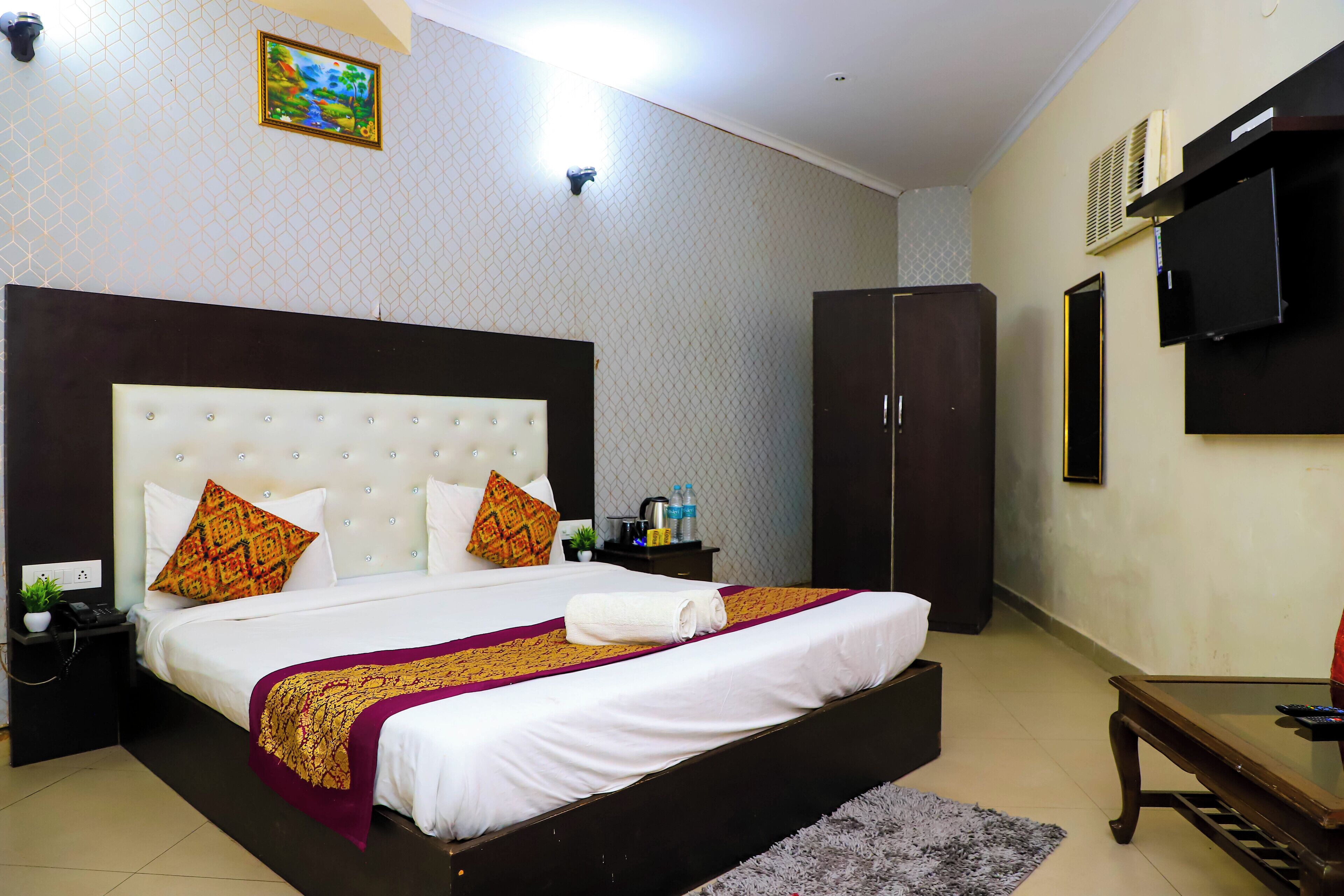 A hotel room with a large bed, a wardrobe, a flat-screen TV, and a small table.