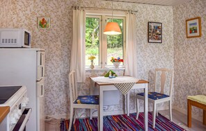 A small room with a window, a table with a checkered tablecloth, two chairs, a microwave, and a colorful rug. - 1 bedroom cozy home in Blentarp (Blentarp)