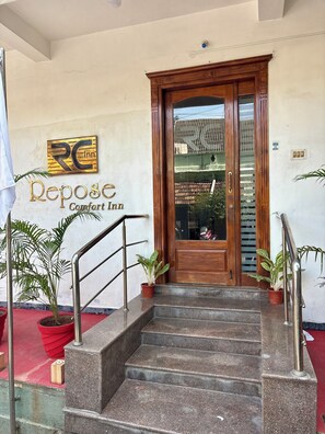 L’entrée d’un hôtel, avec une porte en bois, un escalier et une enseigne indiquant « Repose Comfort Inn ».