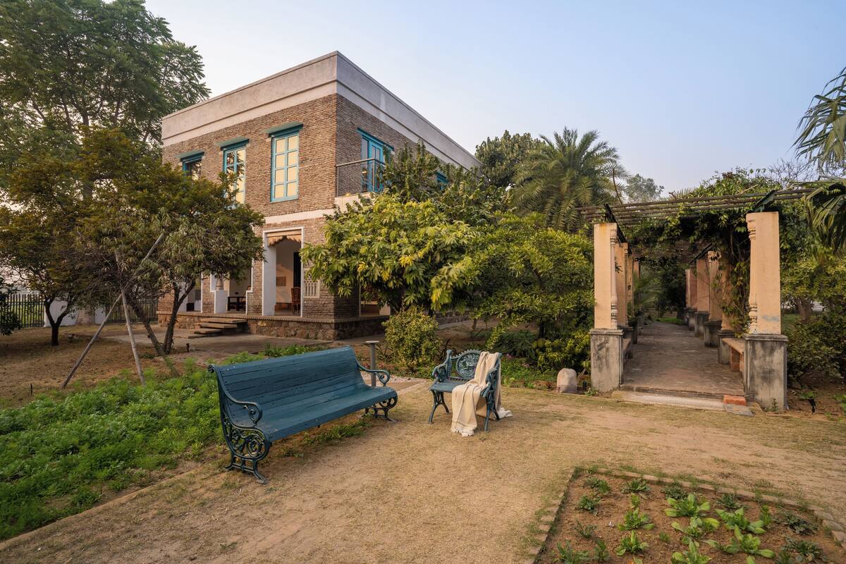 A building with a brick facade, a green bench, and a covered walkway.