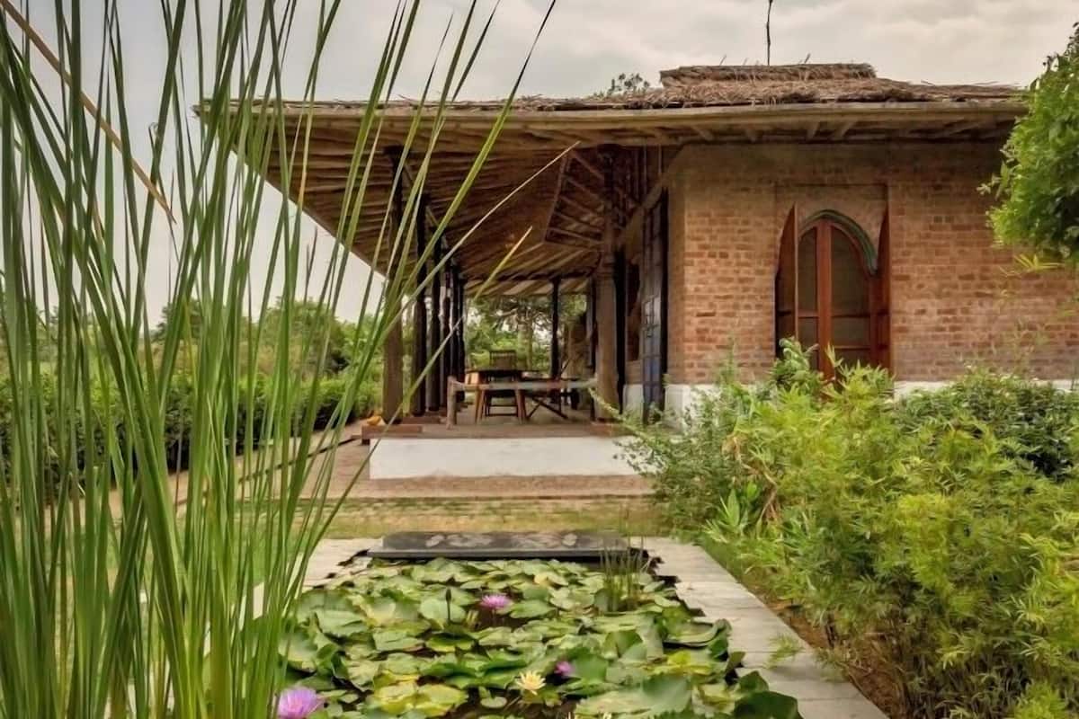 A garden pathway leading to a brick building with a covered outdoor seating area.