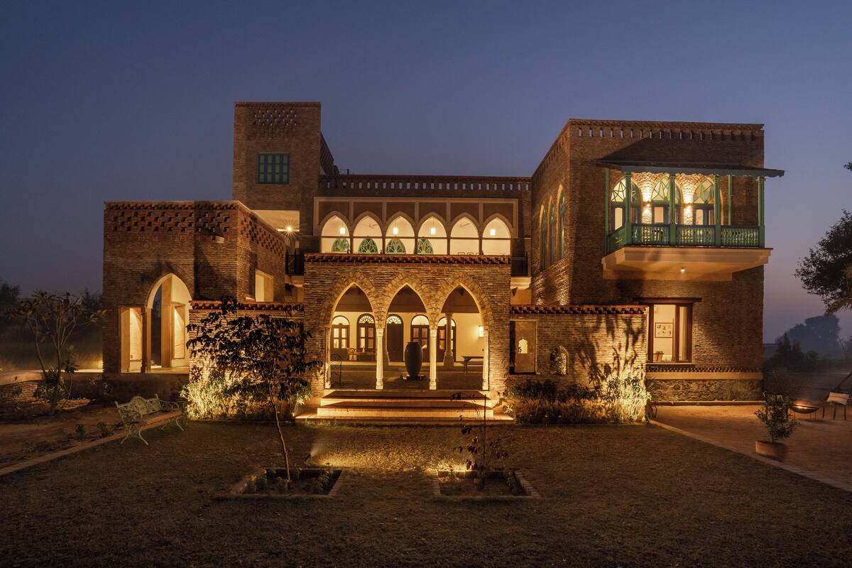 A traditional building with arched windows and a balcony, illuminated at dusk.