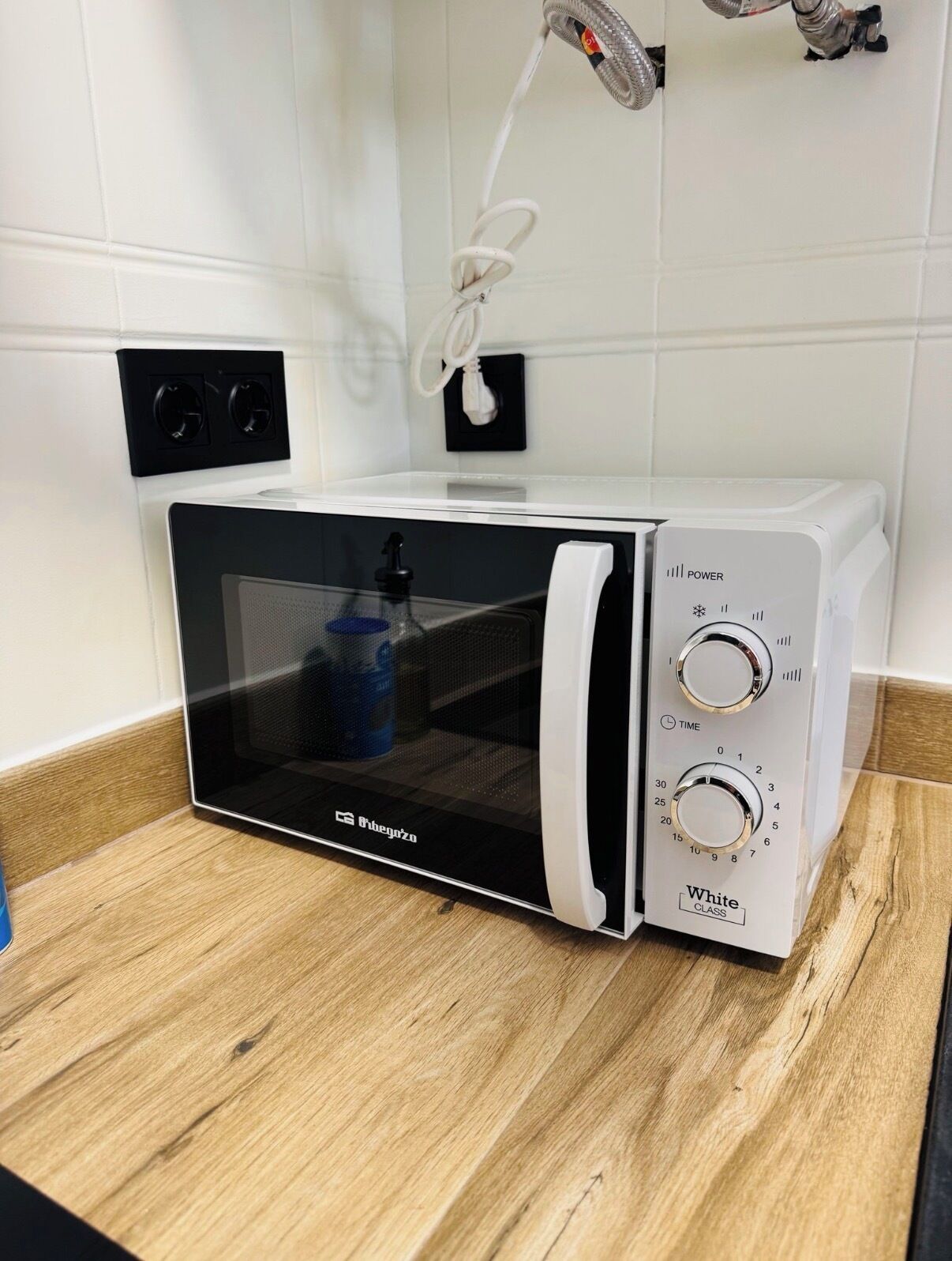 Un horno microondas con pantalla digital, un botón de encendido y una perilla para programar el tiempo.