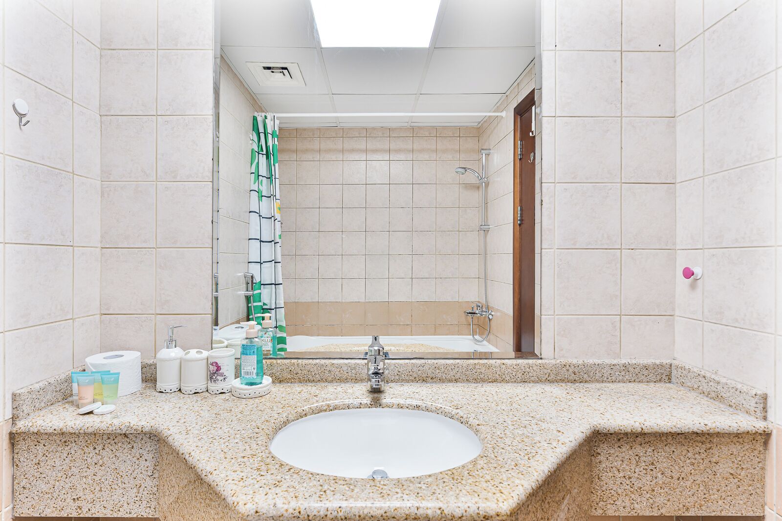Une salle de bain avec un lavabo doté d’un plan de travail en granit, une douche avec une porte en verre et un miroir au-dessus du lavabo.