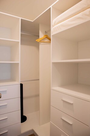 A walk-in closet with open shelves, a hanging rod, and drawers.