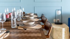 A dining table set with plates, bowls, and cutlery, with chairs around it. - Downtown Views (Dubai)