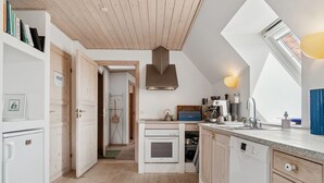 Eine moderne Küche mit Holzausstattung, einem eingebauten Backofen und einem großen Fenster, das für natürliches Licht sorgt.