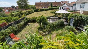 Ein Wohngrundstück mit Rasenfläche, einer Holzterrasse und einer Terrasse mit Gartenmöbeln.