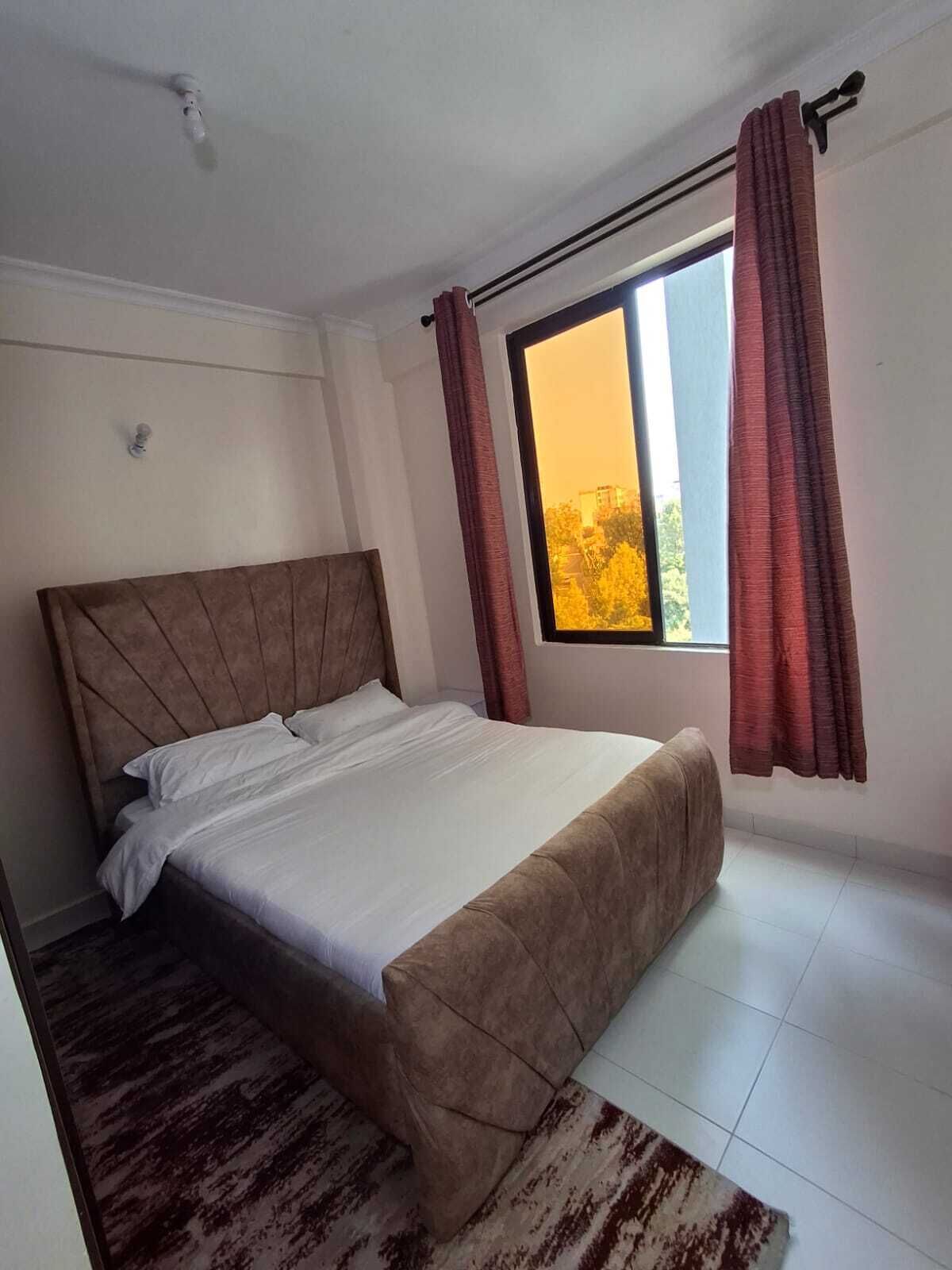 Une chambre à coucher avec un lit, une fenêtre avec des rideaux, une tête de lit et un tapis.